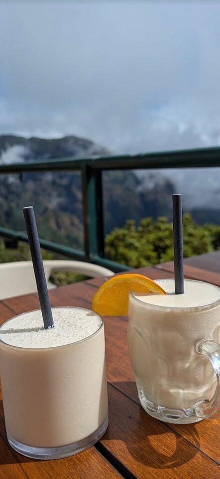 Two cold drinks on a terrace table, mountains behind